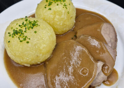 Sauerbraten mit Klößen angerichtet auf einem Teller